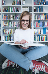 Image showing female student study in library, using tablet and searching for 