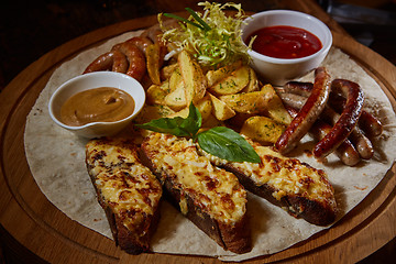 Image showing Assorted fried sausages, grilled potatoes, sauce Adjika, Mustard Sauce