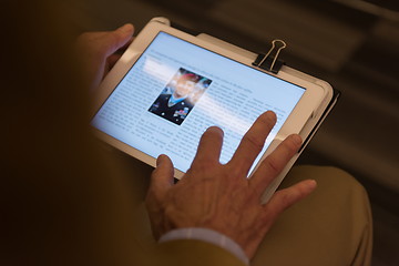 Image showing Closeup of mature hands holding tablet.