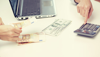 Image showing close up of hands counting money with calculator