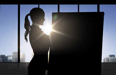 Image showing silhouette of woman with flipboard over office