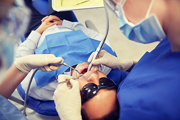 Image showing female dentist treating male patient teeth