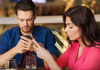 Image showing couple with smartphones dining at restaurant