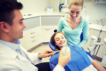 Image showing happy dentist showing toothbrush to patient girl