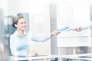 Image showing businesswoman taking papers from someone in office