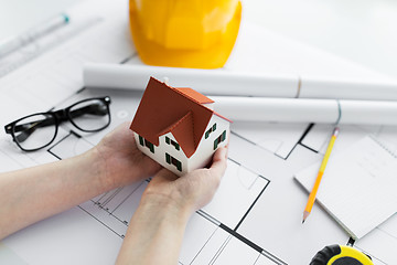 Image showing close up of hands with house model above blueprint