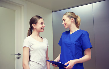 Image showing smiling nurse with clipboard and girl at hospital