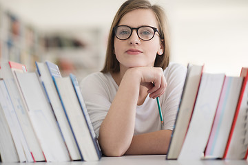 Image showing portrait of famale student selecting book to read in library