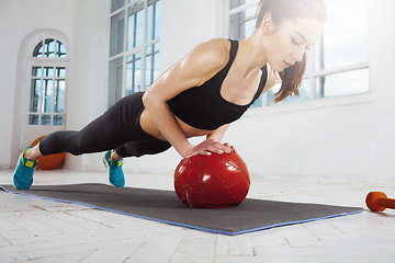 Image showing Beautiful slim brunette doing some gymnastics at the gym