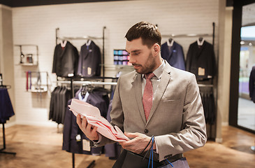 Image showing man with bags choosing shirt in clothing store