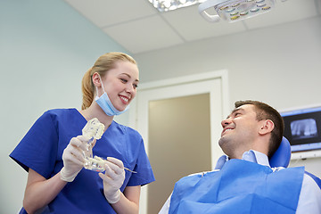 Image showing happy dentist showing jaw layout to male patient