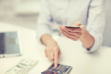 Image showing close up of woman counting money with calculator