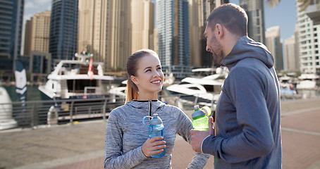 Image showing smiling couple with bottles of water in city