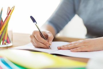 Image showing close up of student writing to notebook at home