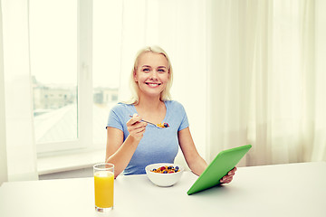 Image showing woman with tablet pc eating breakfast at home