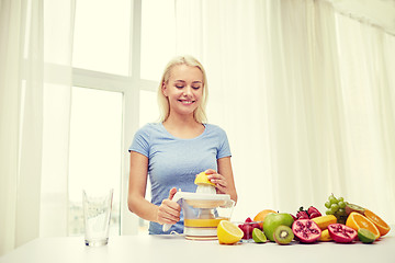 Image showing smiling woman squeezing fruit juice at home