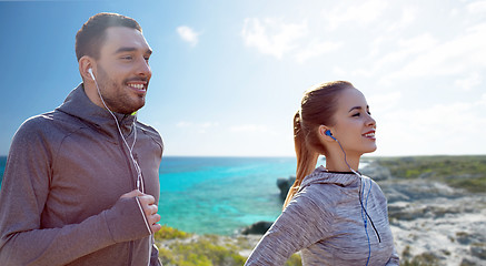 Image showing happy couple with earphones running in city