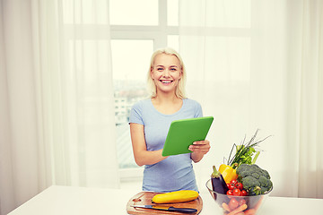 Image showing smiling young woman with tablet pc cooking at home