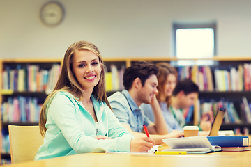 Image showing happy student girl writing to notebook in library