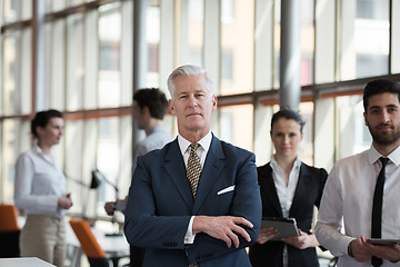 Image showing portrait of senior businessman as leader  with group of people i