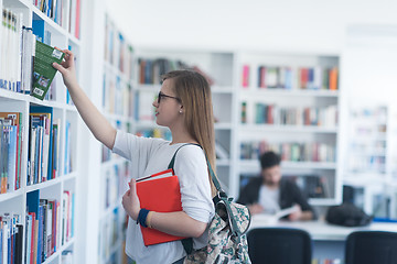 Image showing famale student selecting book to read in library