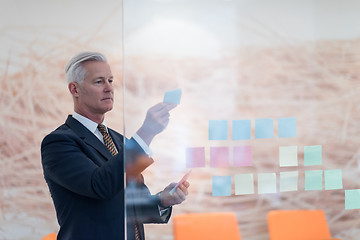 Image showing senior business man making plans with sticker