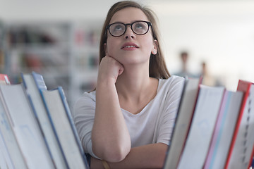 Image showing portrait of famale student selecting book to read in library