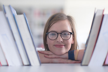 Image showing portrait of famale student selecting book to read in library