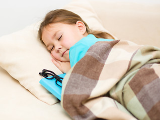 Image showing Girl is sleeping with her book and glasses