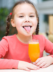 Image showing Little girl is drinking orange juice