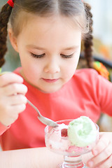 Image showing Little girl is eating ice-cream in parlor