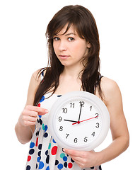 Image showing Young woman is holding big clock