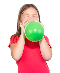 Image showing Little girl is inflating green balloon