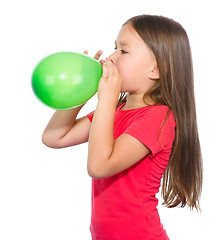Image showing Little girl is inflating green balloon