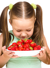 Image showing Happy little girl is eating strawberries