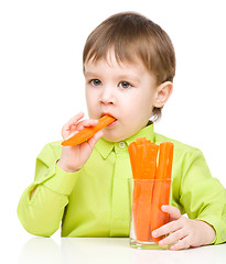 Image showing Little boy is eating carrot