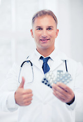 Image showing young male doctor with packs of pills