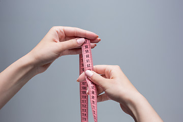 Image showing The tape in female hands on gray background. Weight loss, diet