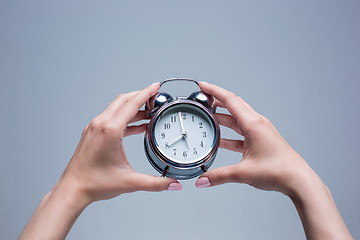 Image showing The female hands and old style alarm clock 