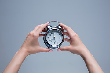 Image showing The female hands and old style alarm clock 