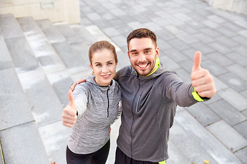 Image showing smiling couple showing thumbs up on city street