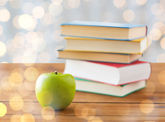 Image showing close up of books and green apple on wooden table