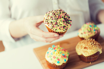 Image showing close up of woman with glazed cupcakes or muffins