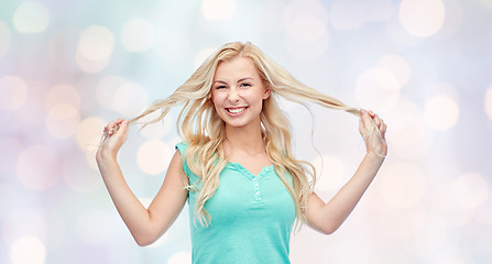 Image showing smiling young woman holding strands of her hair