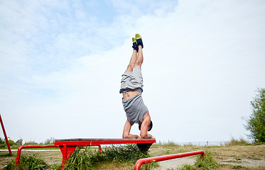 Image showing young man exercising on bench outdoors