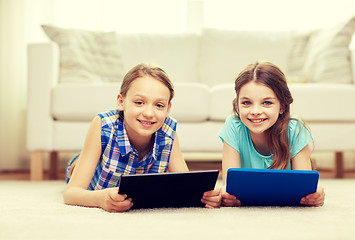 Image showing happy girls with tablet pc lying on floor at home