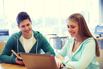 Image showing happy students with laptop and books at library