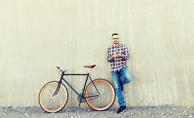 Image showing hipster man in earphones with smartphone and bike