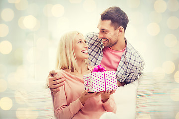 Image showing happy man giving woman present over holiday lights
