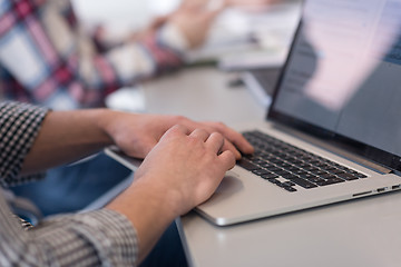 Image showing close up of business man hands typing on laptop with team on mee